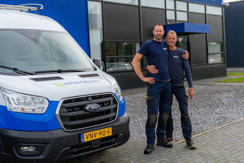 Airco monteurs naast elkaar met een bedrijfsbus
