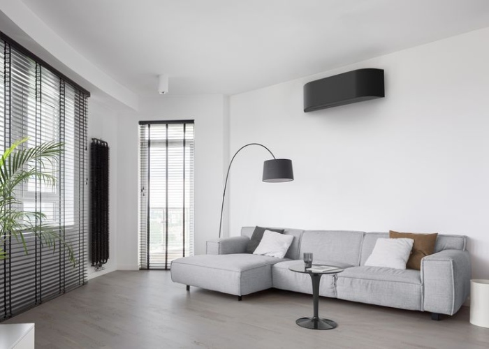 Een lichte, moderne woonkamer met een geïnstalleerde zwarte airco aan de muur
