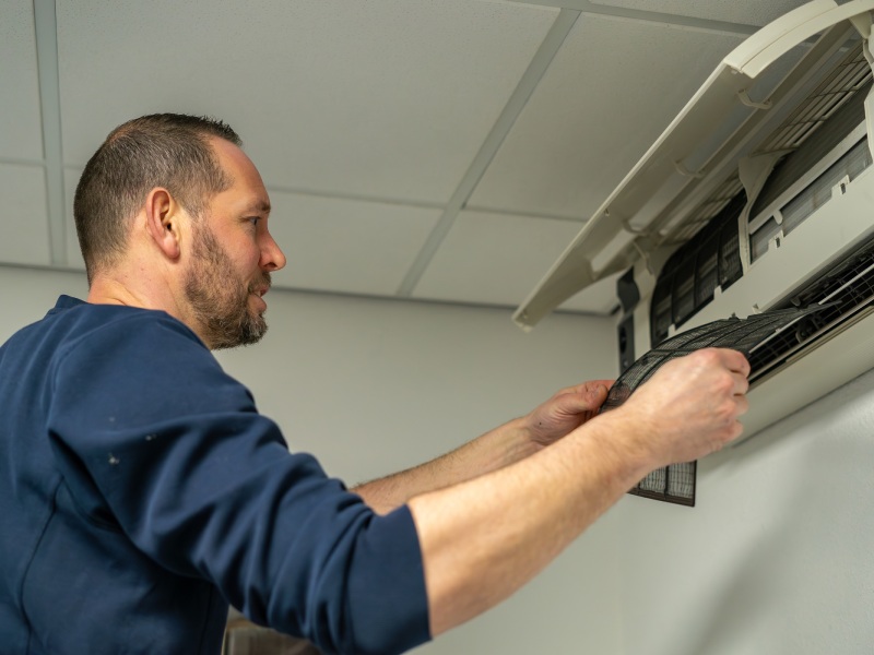 Een technicus die bezig is met het installeren van een airco in Hoogeveen