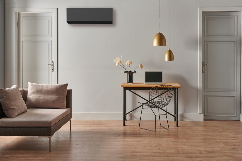 Modern ingerichte woonkamer met links een zithoek, rechts een klein bureau en aan de muur een stijlvol geïntegreerde airco van het merk Toshiba