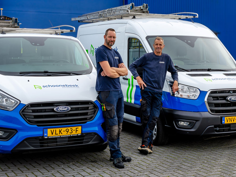 Twee monteurs leunend tegen de bedrijsbussen van Schoonebeek