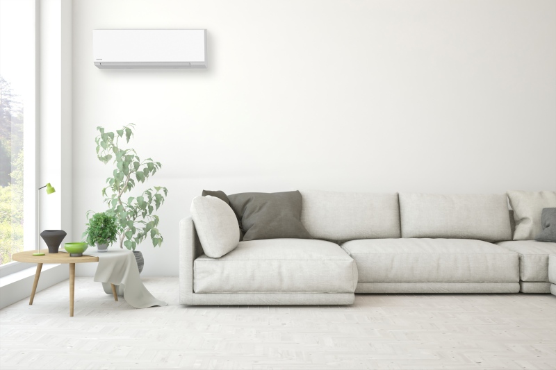 Stijlvolle woonkamer met een witte bank, witte muren en een airco systeem van toshiba dat naadloos aansluit bij de omgeving